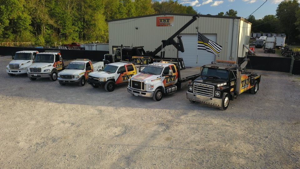 Five decorated utility trucks parked outside a building, including white, orange, and black vehicles with flags.