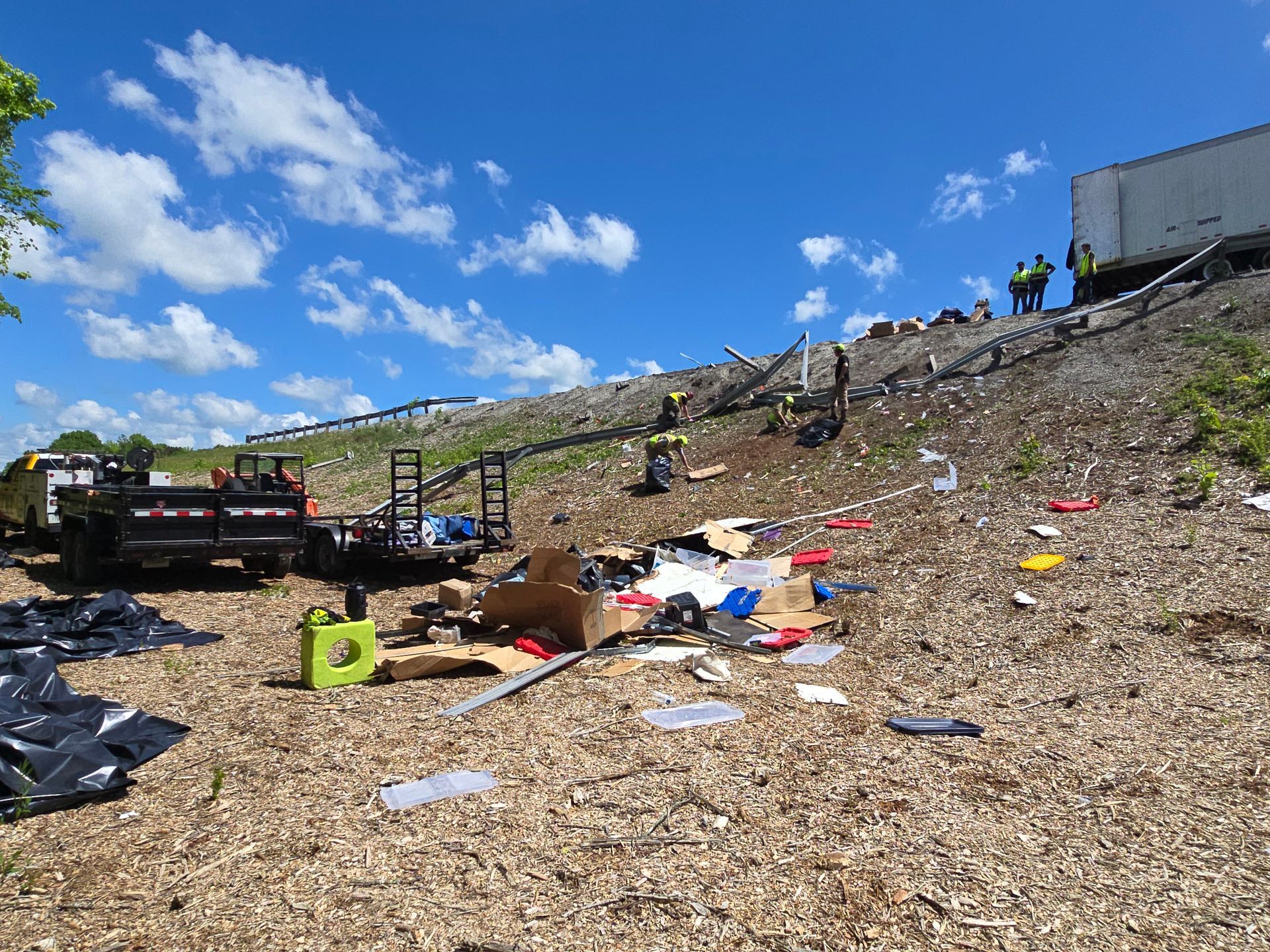 Trash-strewn hillside with debris and a truck under a blue sky, resembling an illegal dump site.