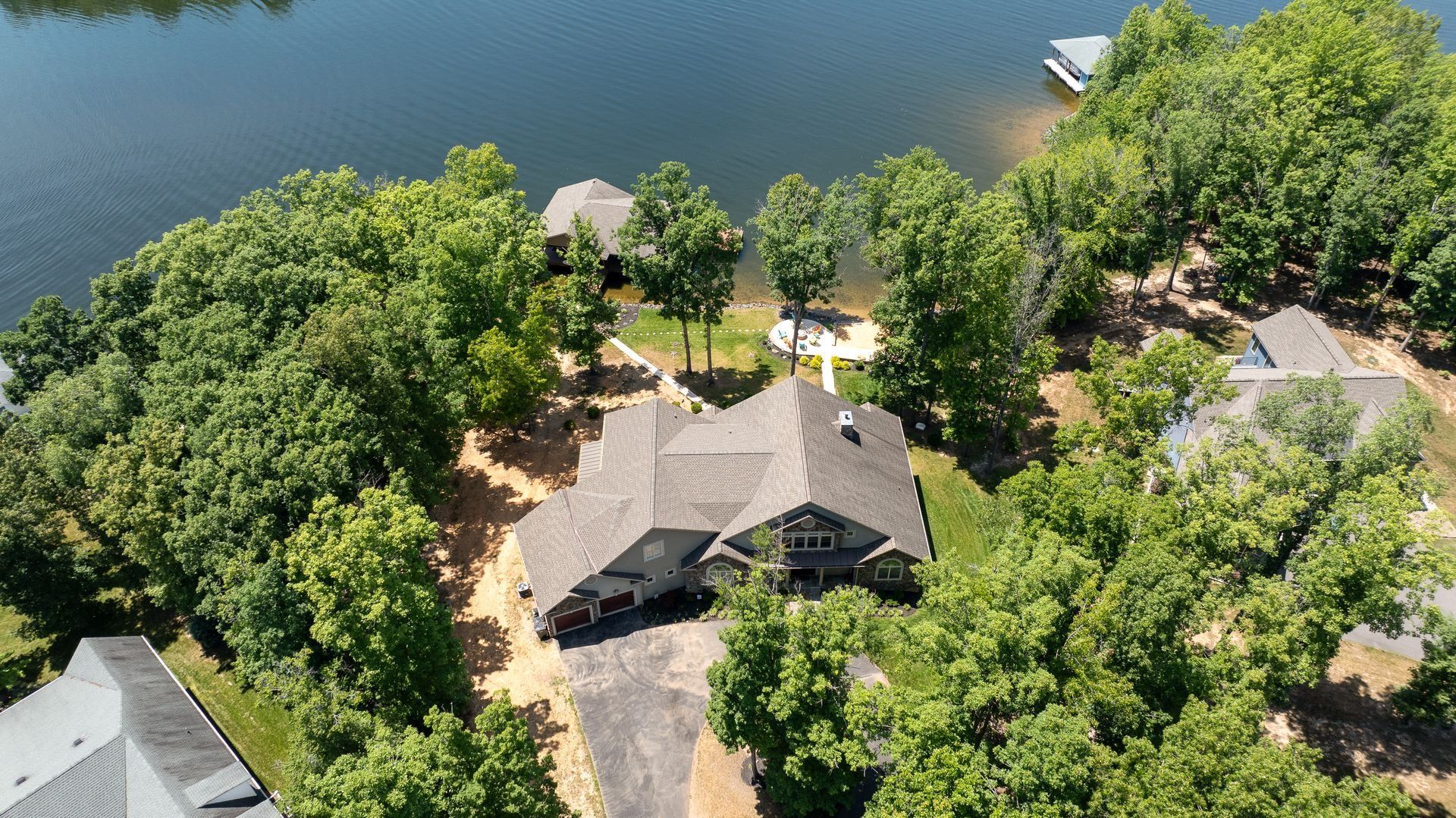 Aerial view of a house surrounded by trees and overlooking a lake.