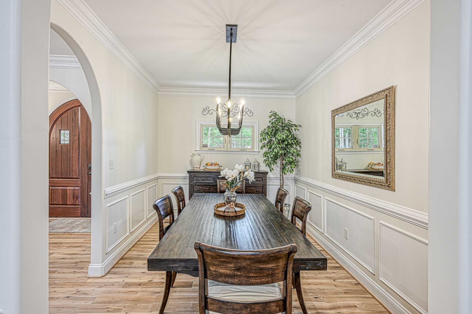 Dining room with a long wooden table, chairs, and chandelier.
