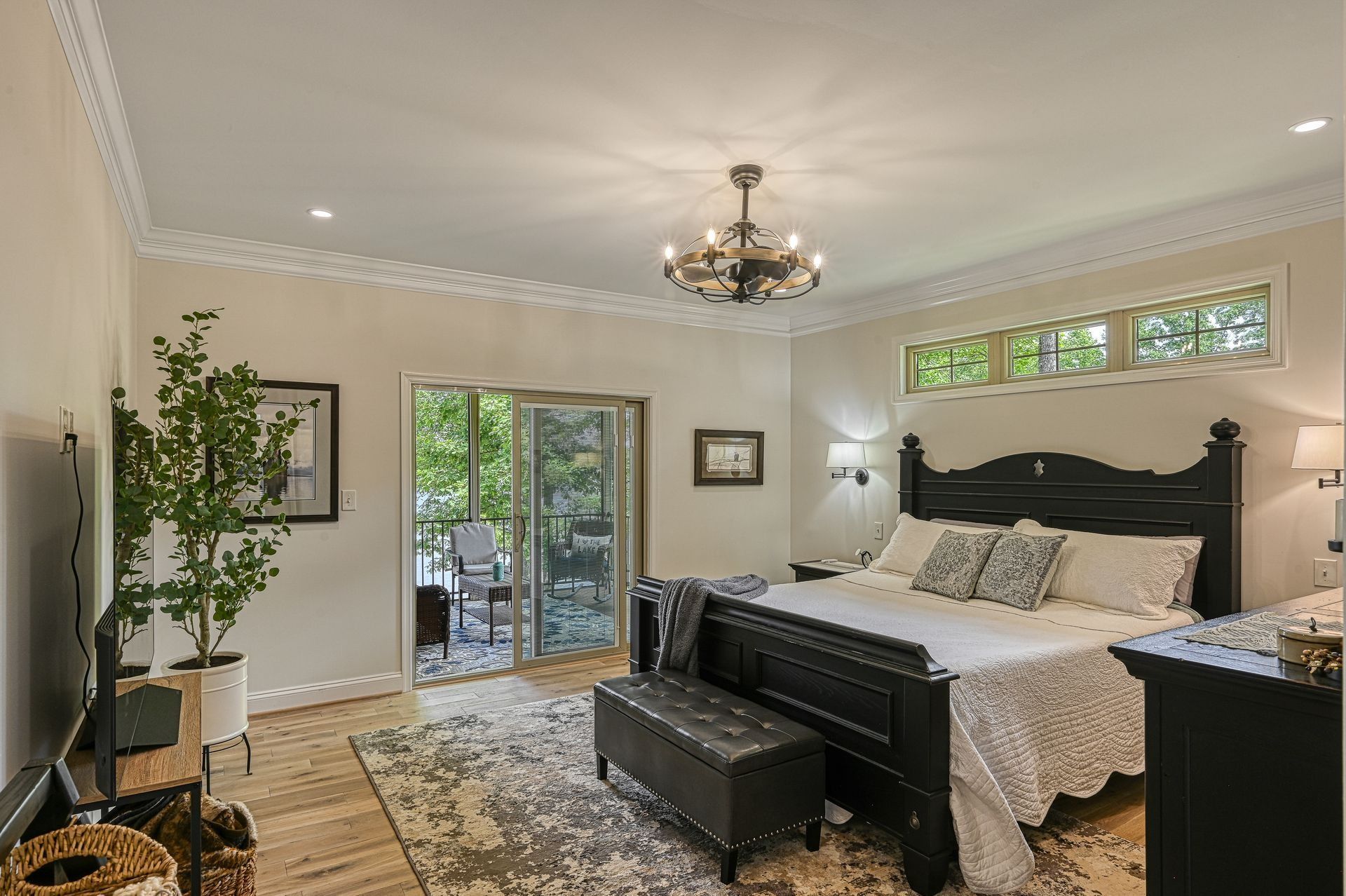 Bedroom with black bed, chandelier, sliding door to balcony, neutral tones.
