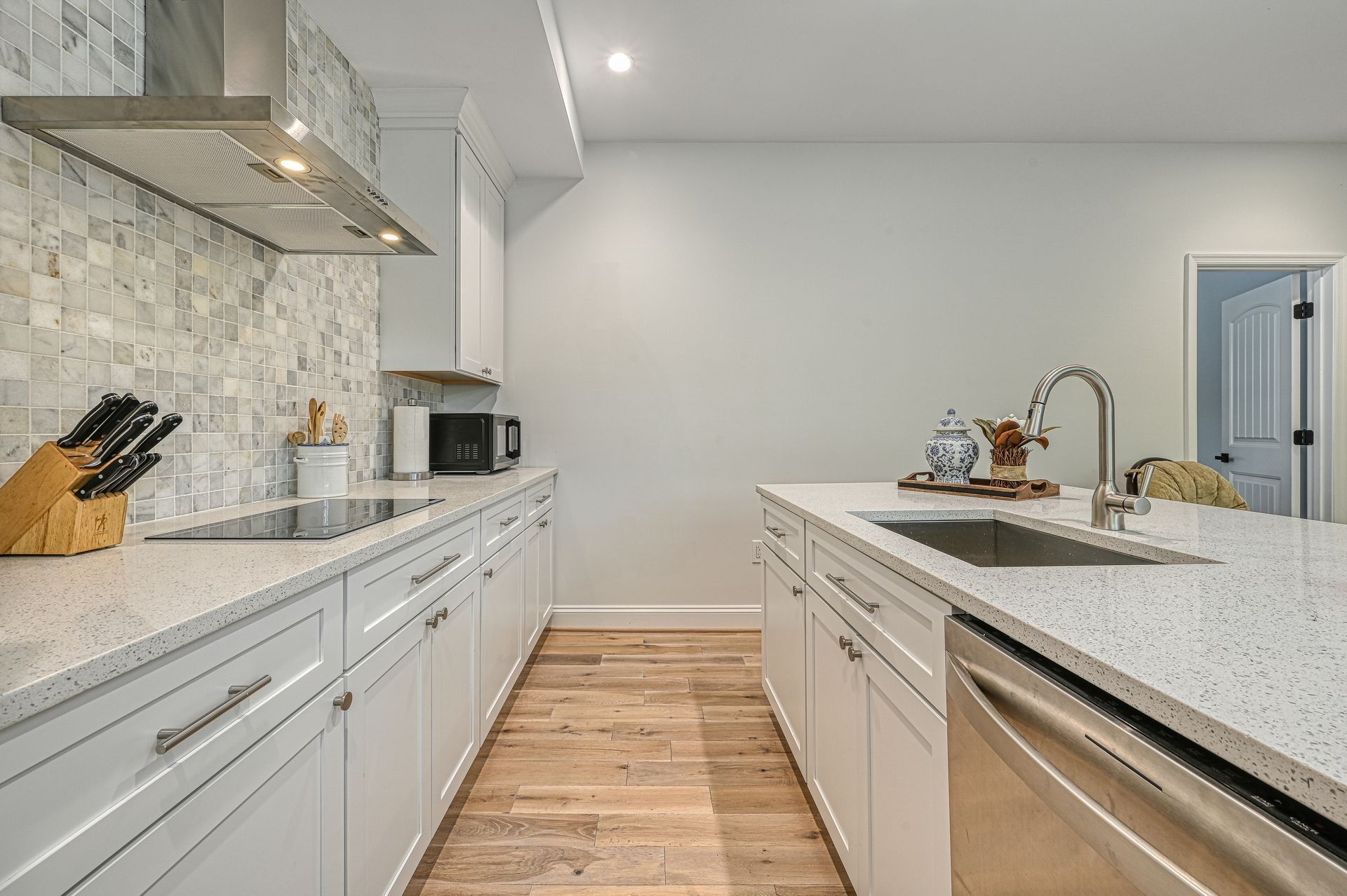 Modern kitchen with white cabinets, quartz countertops, and a stainless steel sink.