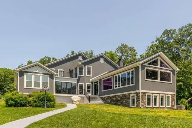 Gray house with a stone and wood facade, multiple windows, and a grassy yard.