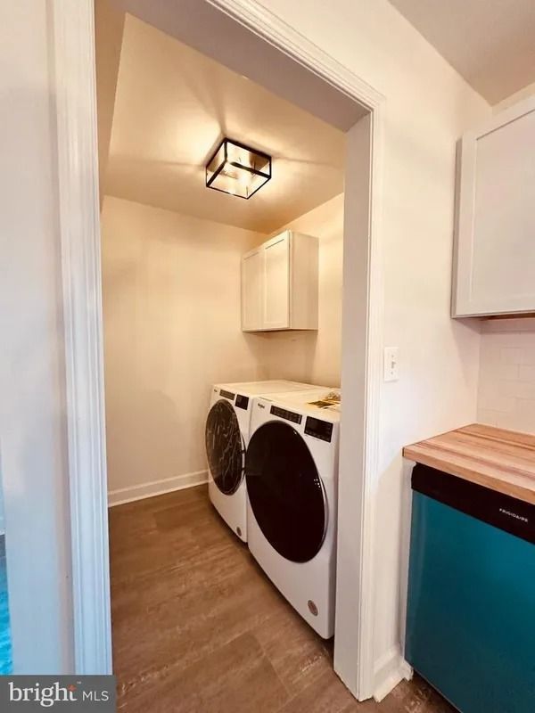 Laundry room with washer, dryer, cabinets, and a teal countertop.