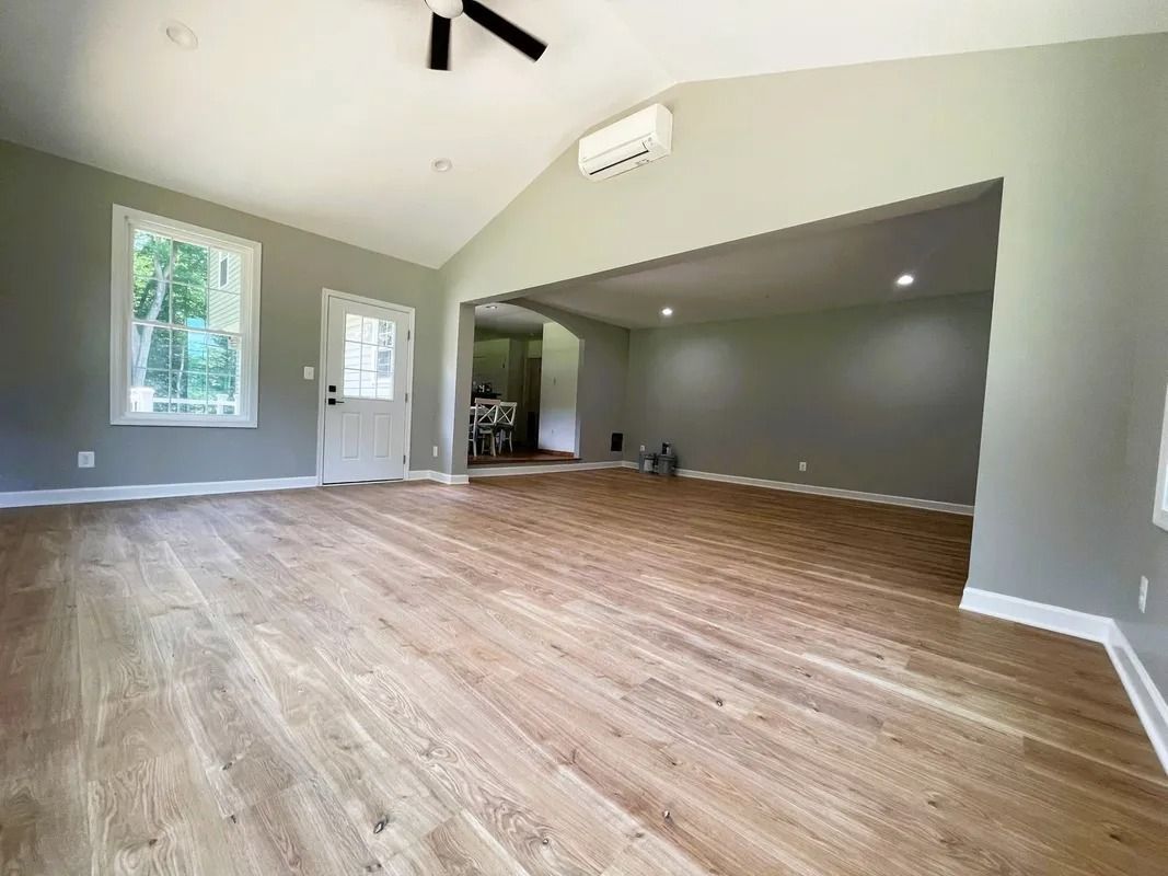 Empty room with hardwood floors, gray walls, white trim, and a high ceiling.