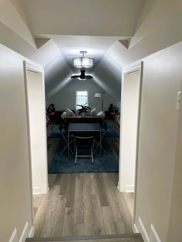 View of a room with slanted ceiling. Table and chairs on blue rug; doorways on either side.