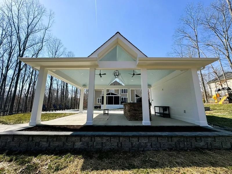 Covered outdoor patio with white pillars, ceiling fans, and a built-in grill area.
