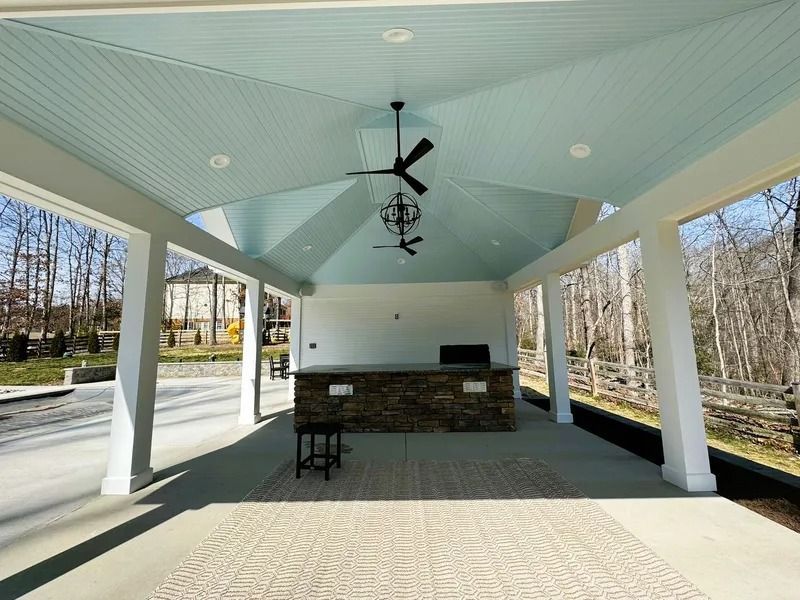 Covered outdoor patio with light blue ceiling, white columns, and a stone bar.