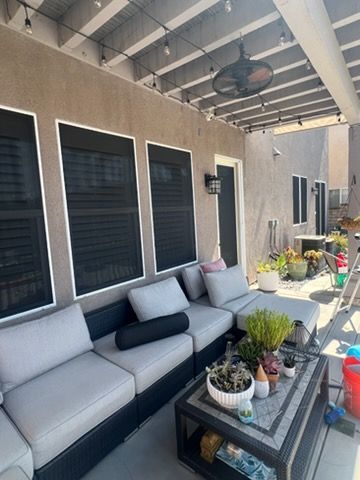A patio with gray sectional sofas, a coffee table with plants, and string lights under a covered pergola.