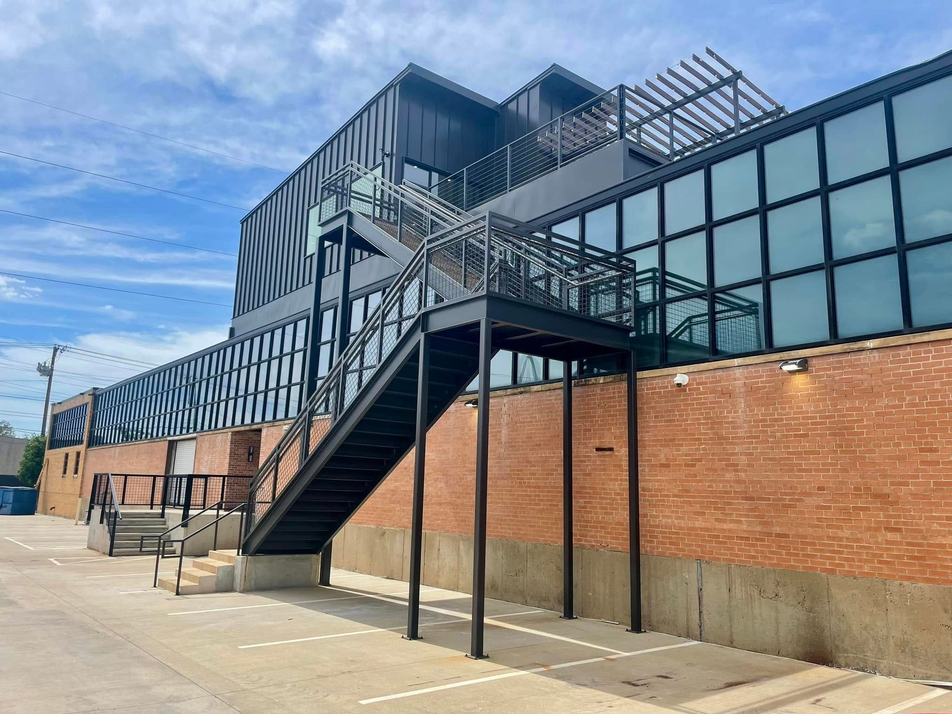 Modern brick building with exterior metal staircase and large glass windows under a blue sky