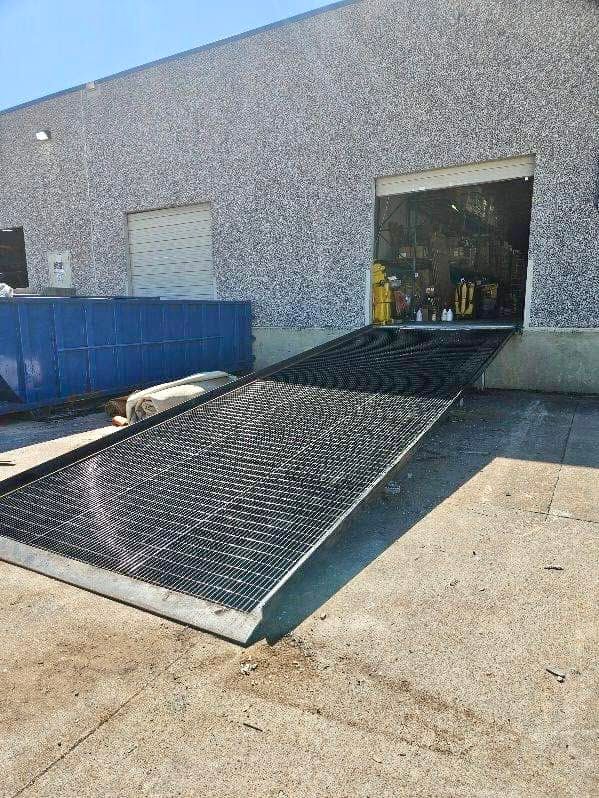 Industrial loading dock with a metal ramp leading to an open warehouse doorway.