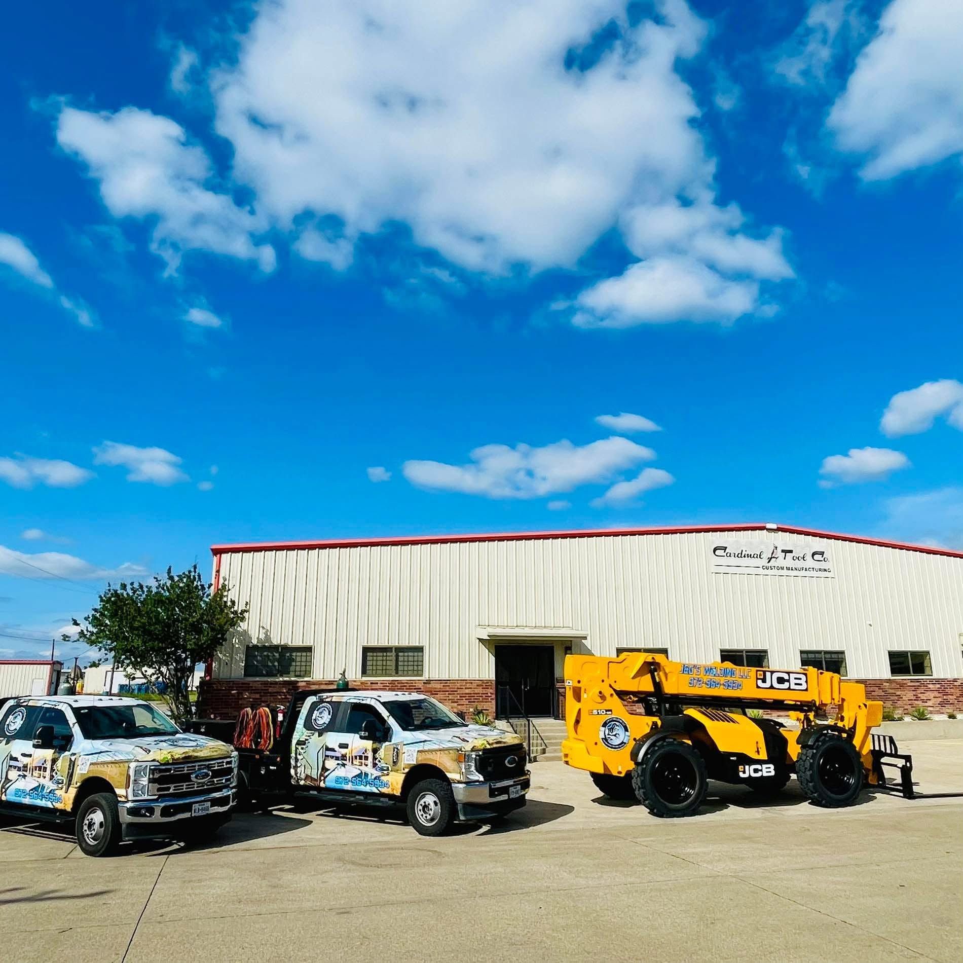 Two branded pickup trucks and a yellow utility vehicle parked outside a warehouse under a blue sky.