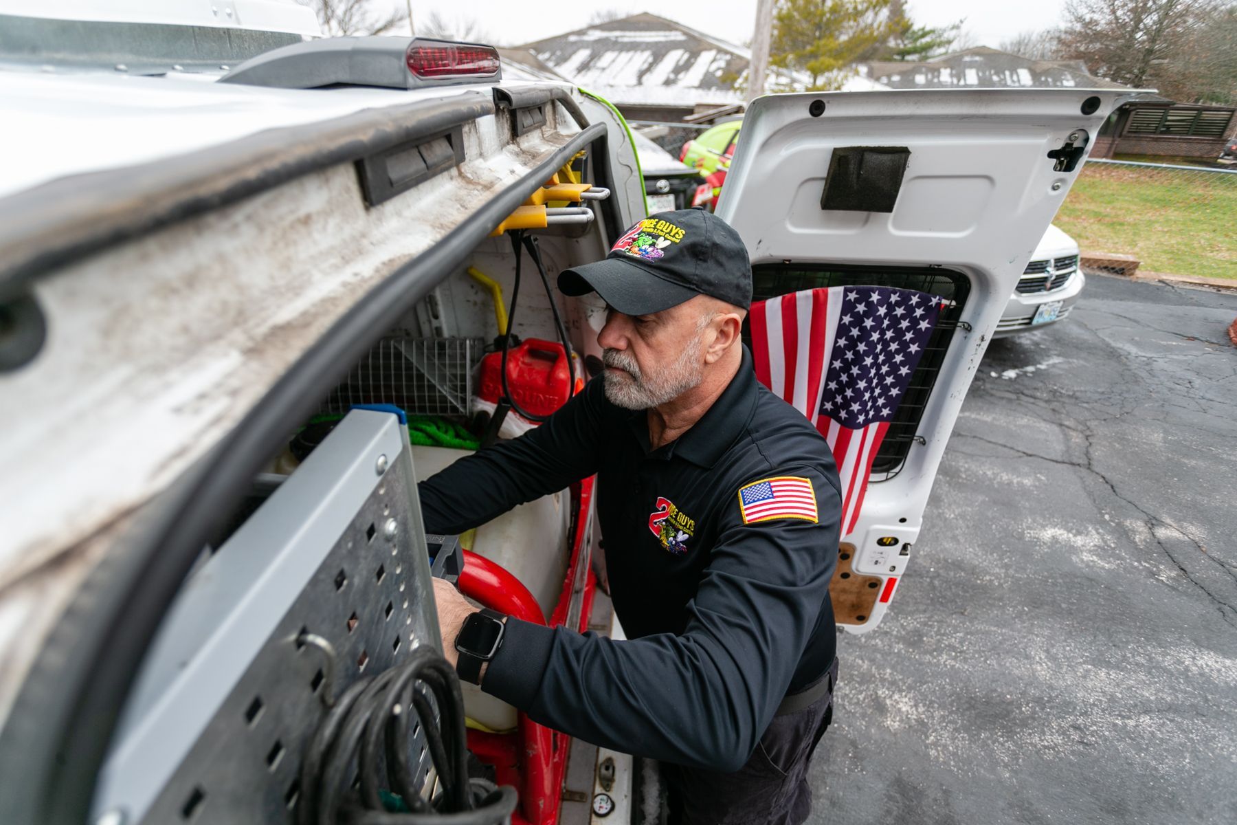 Worker inspecting equipment beside a white truck with an American flag in the back