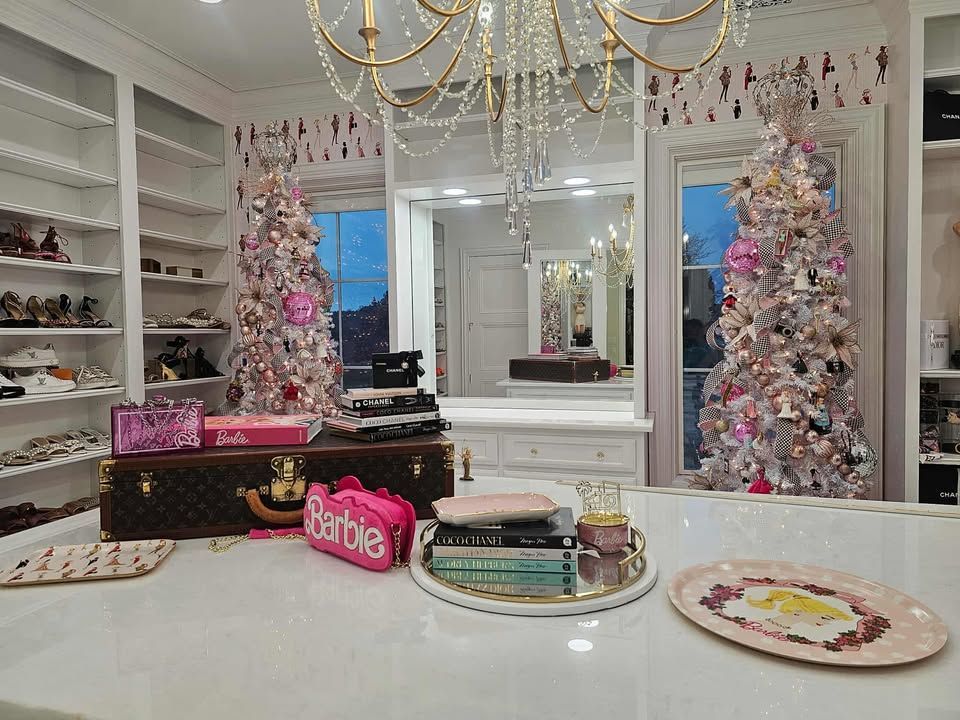 Elegant white room with pink Christmas trees, mirrored decor, and a Barbie display on a vanity.