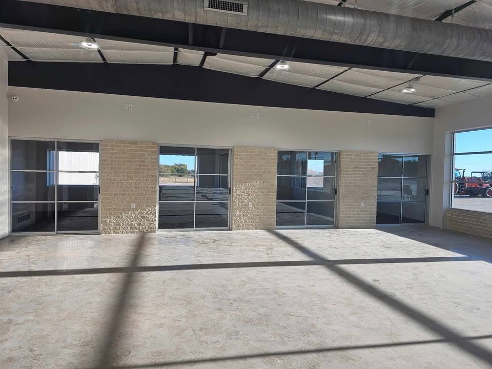 Empty covered patio with brick columns, glass doors, and long shadows on the concrete floor