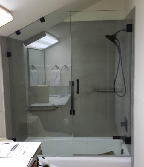 Modern bathroom with glass shower enclosure, wall-mounted showerhead, mirror, and sink counter