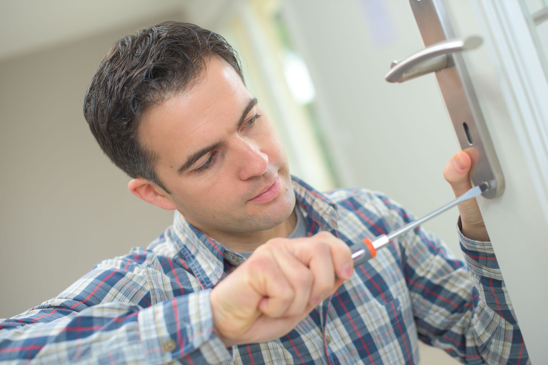 Man using a screwdriver to install a door handle.