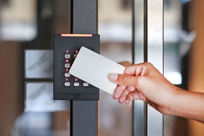 Hand using access card on a keypad door lock.