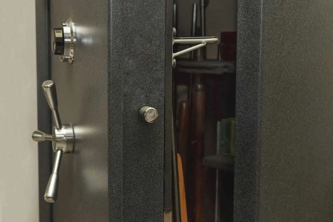Gun safe with the door partially open, revealing rifles inside.