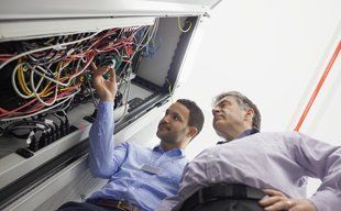 Two guys looking at a computer network wiring