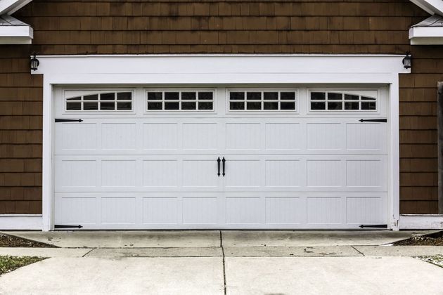 White double garage door with windows on a brown shingled house exterior