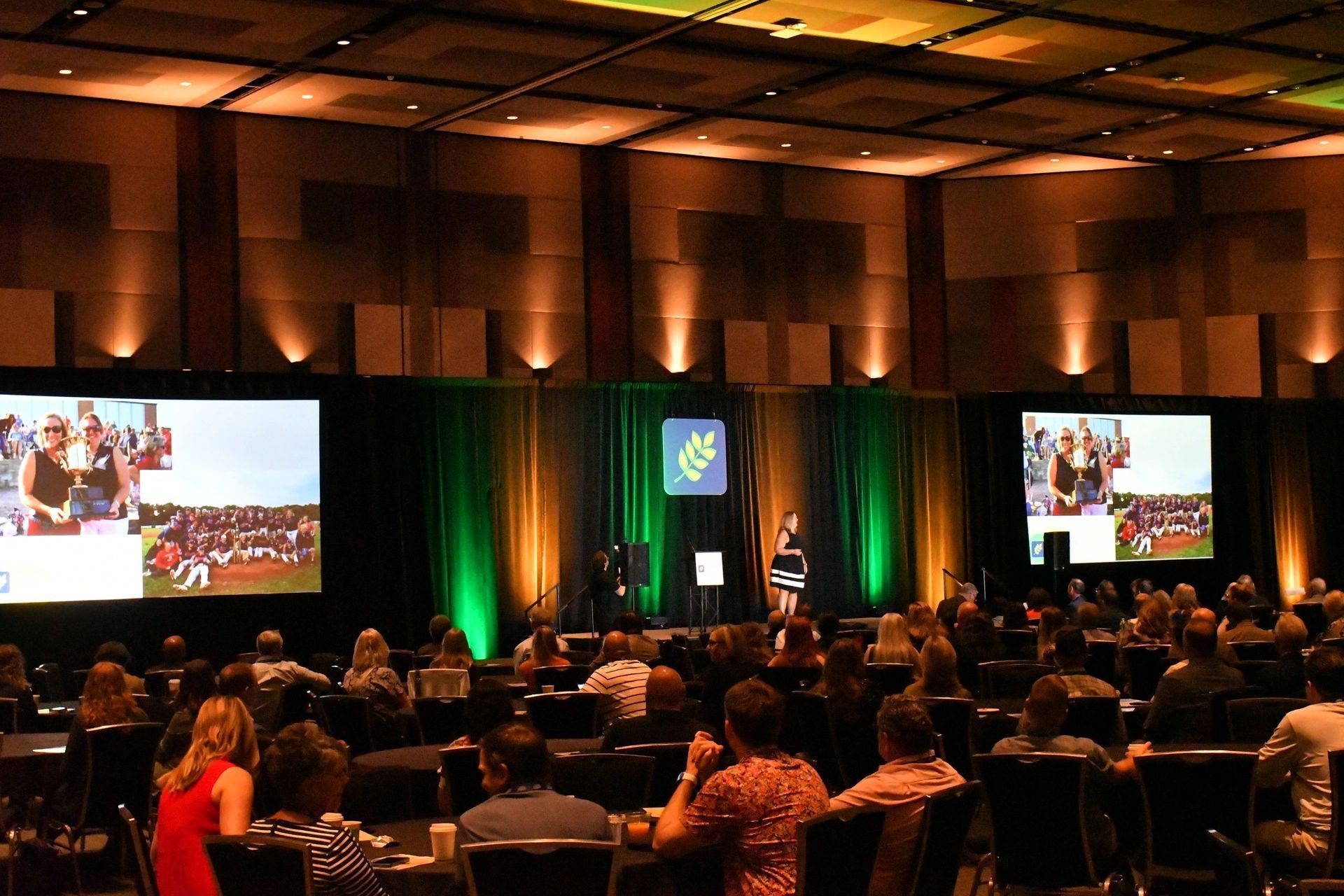 A group of people are sitting in a large room watching a presentation