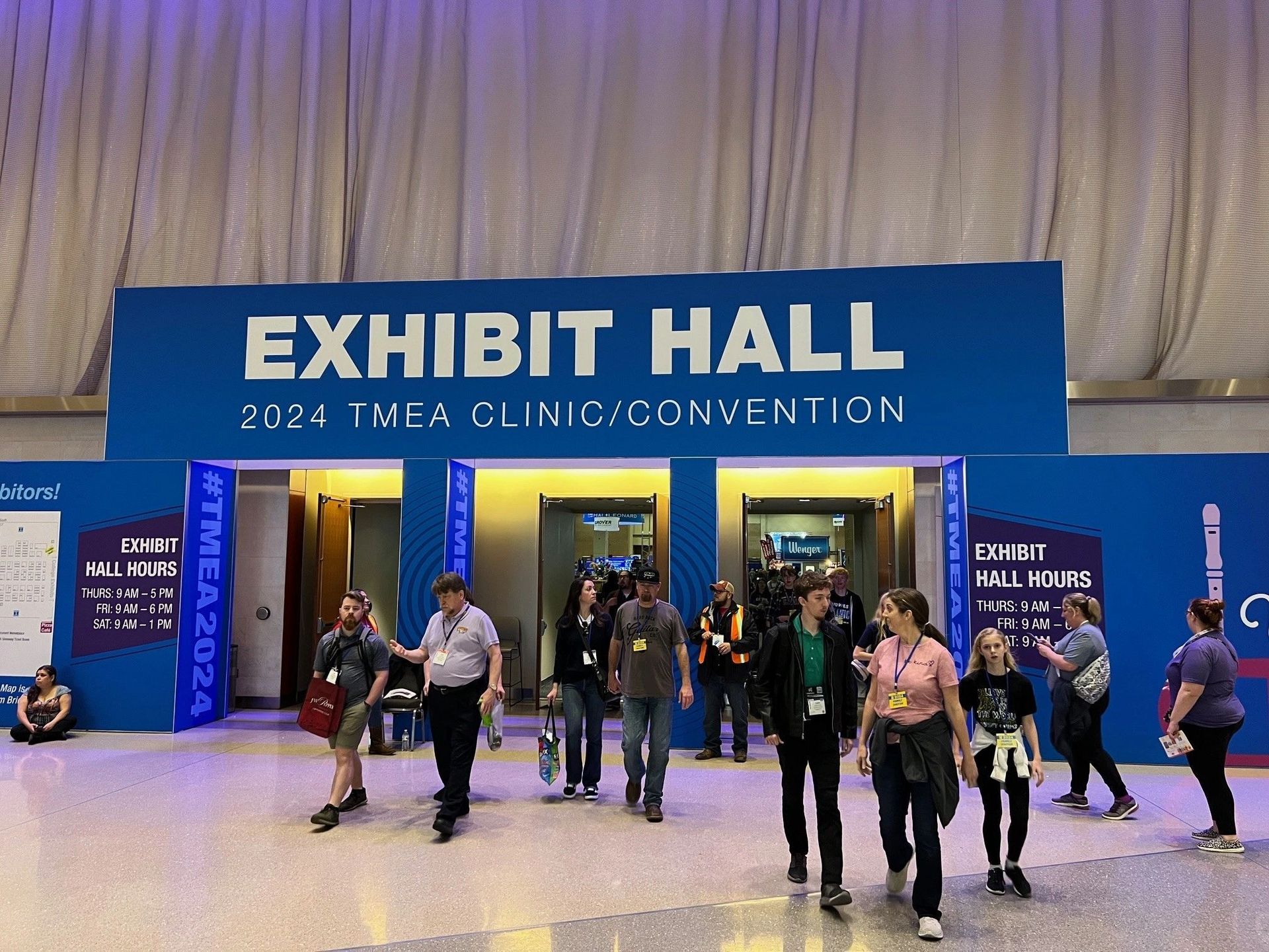 A group of people are walking into the exhibit hall