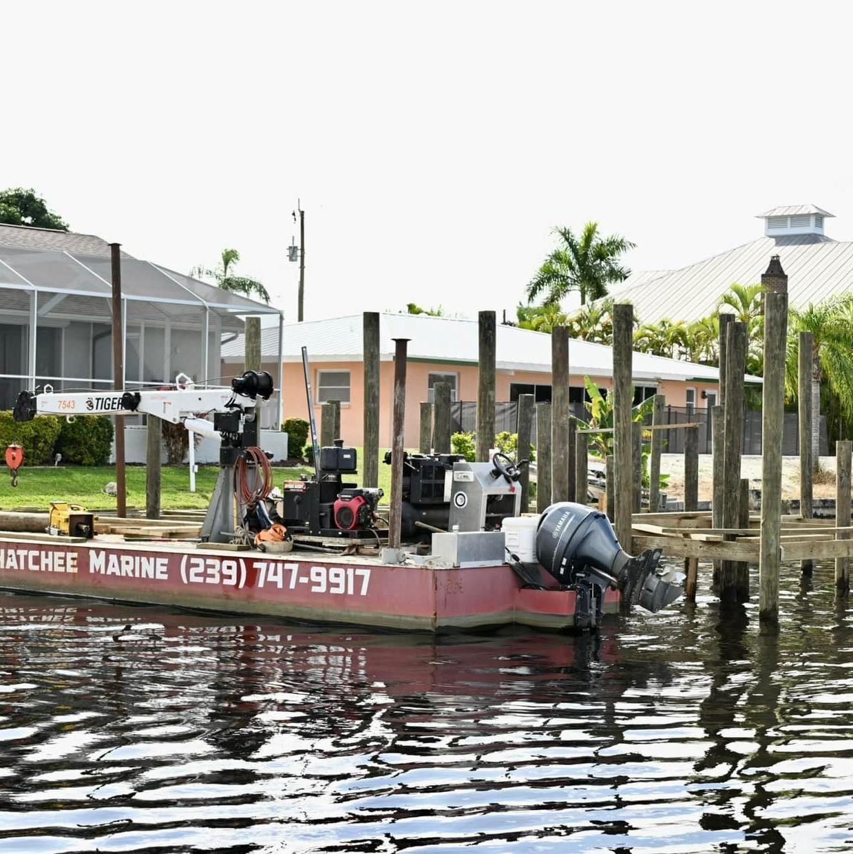 A boat with the number 239 747-9977 on the side is docked at a dock