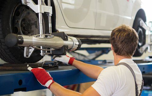 Mechanic checking wheel alignment in a car workshop