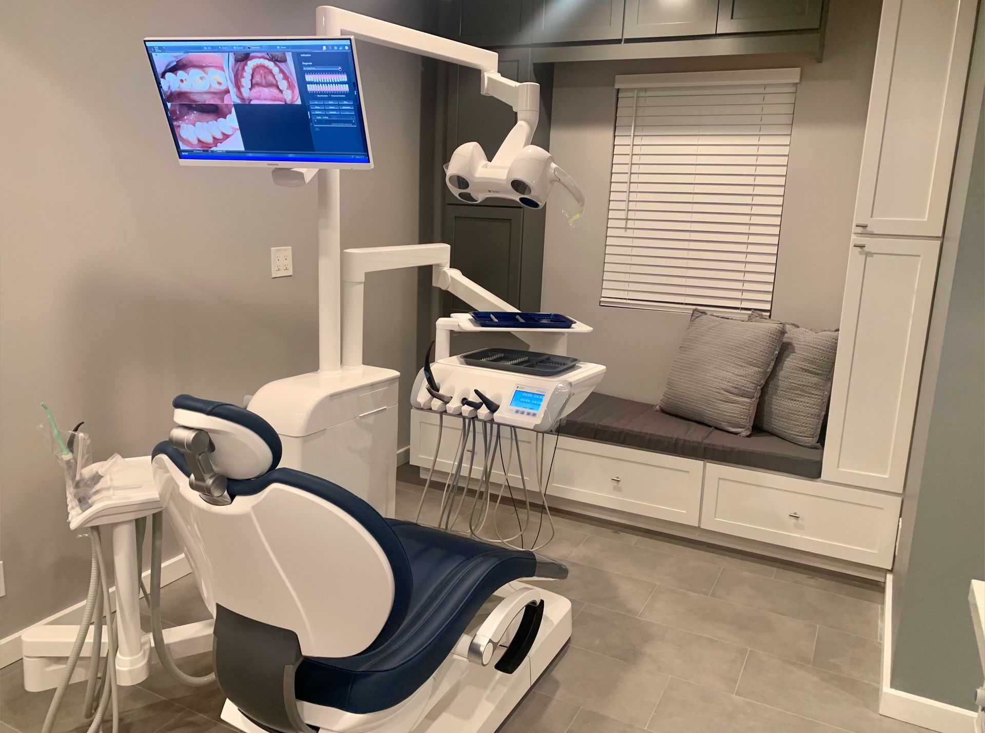 Dental office interior with two blue and white dental chairs, equipment, and monitors.