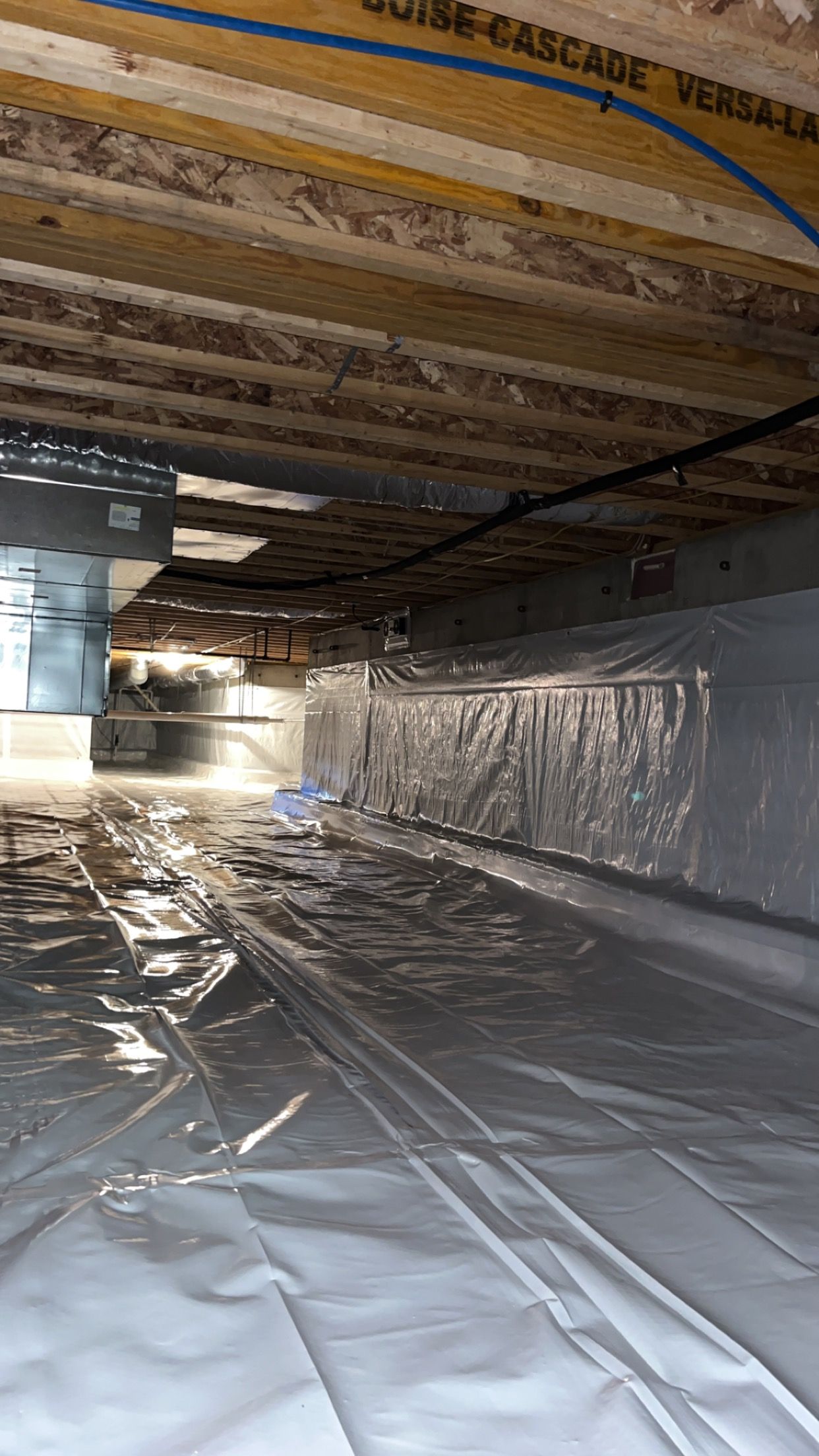 A crawl space under a house with a lot of plastic on the floor.