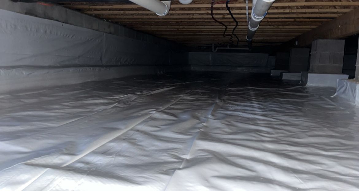 A crawl space filled with plastic and pipes.