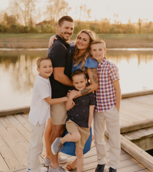 A family posing for a picture on a dock near a lake