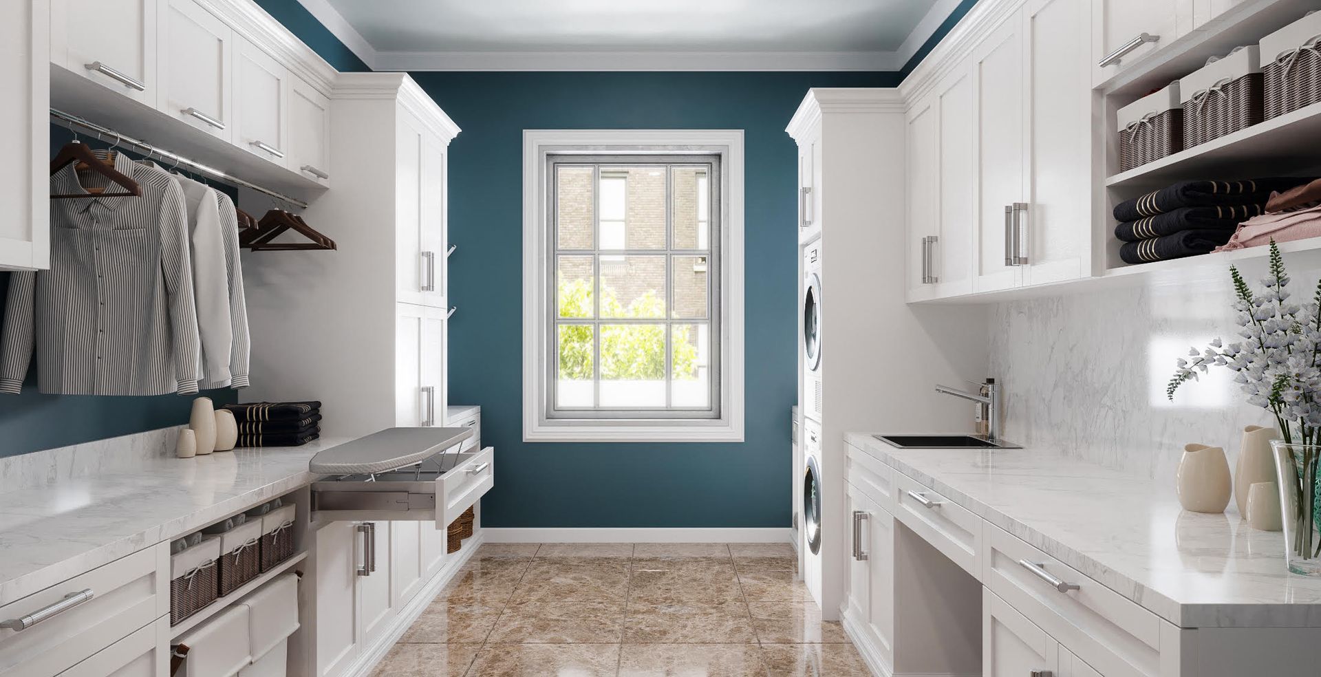 White laundry room with blue accent wall, featuring cabinets, sink, window, and ironing board.