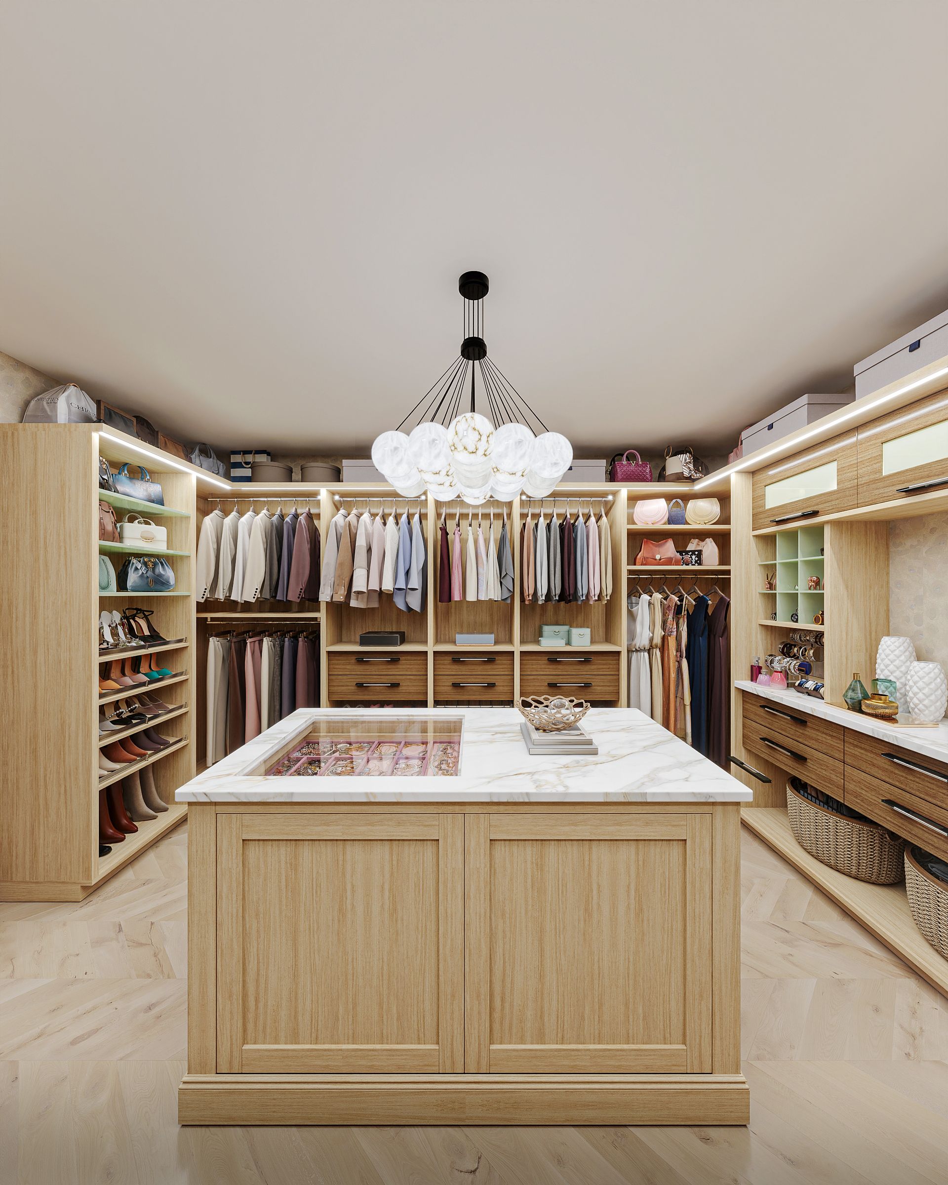 Luxurious walk-in closet with light wood cabinetry and an island. Clothes, shoes, and accessories are organized with a central chandelier.