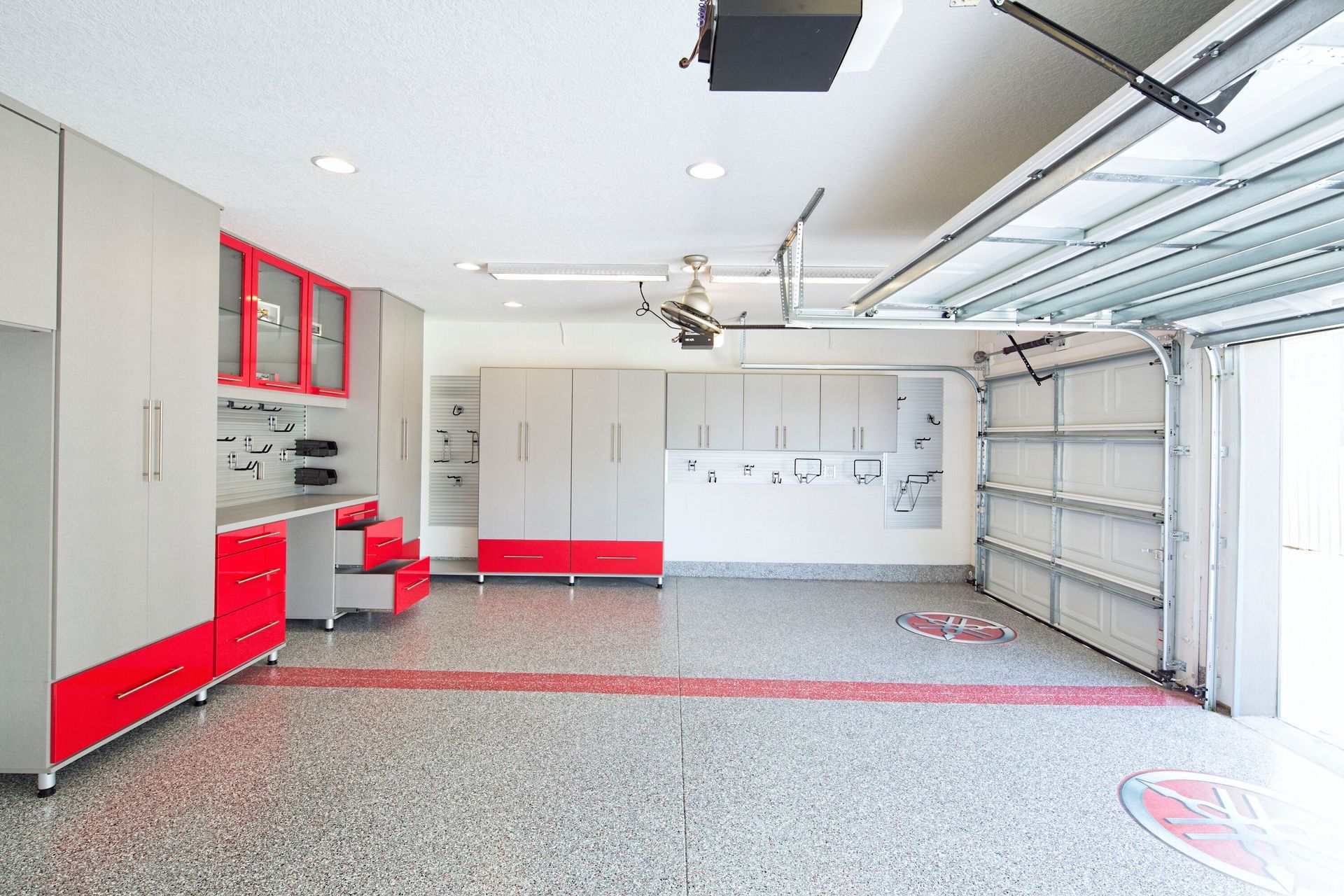 Organized garage with gray and red storage cabinets, epoxy floor, and open garage door.