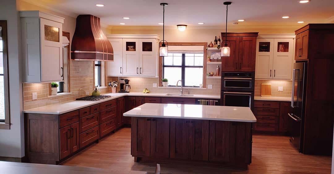 A kitchen featuring a dark wood island, matching perimeter cabinets, white upper cabinets, and white countertops.