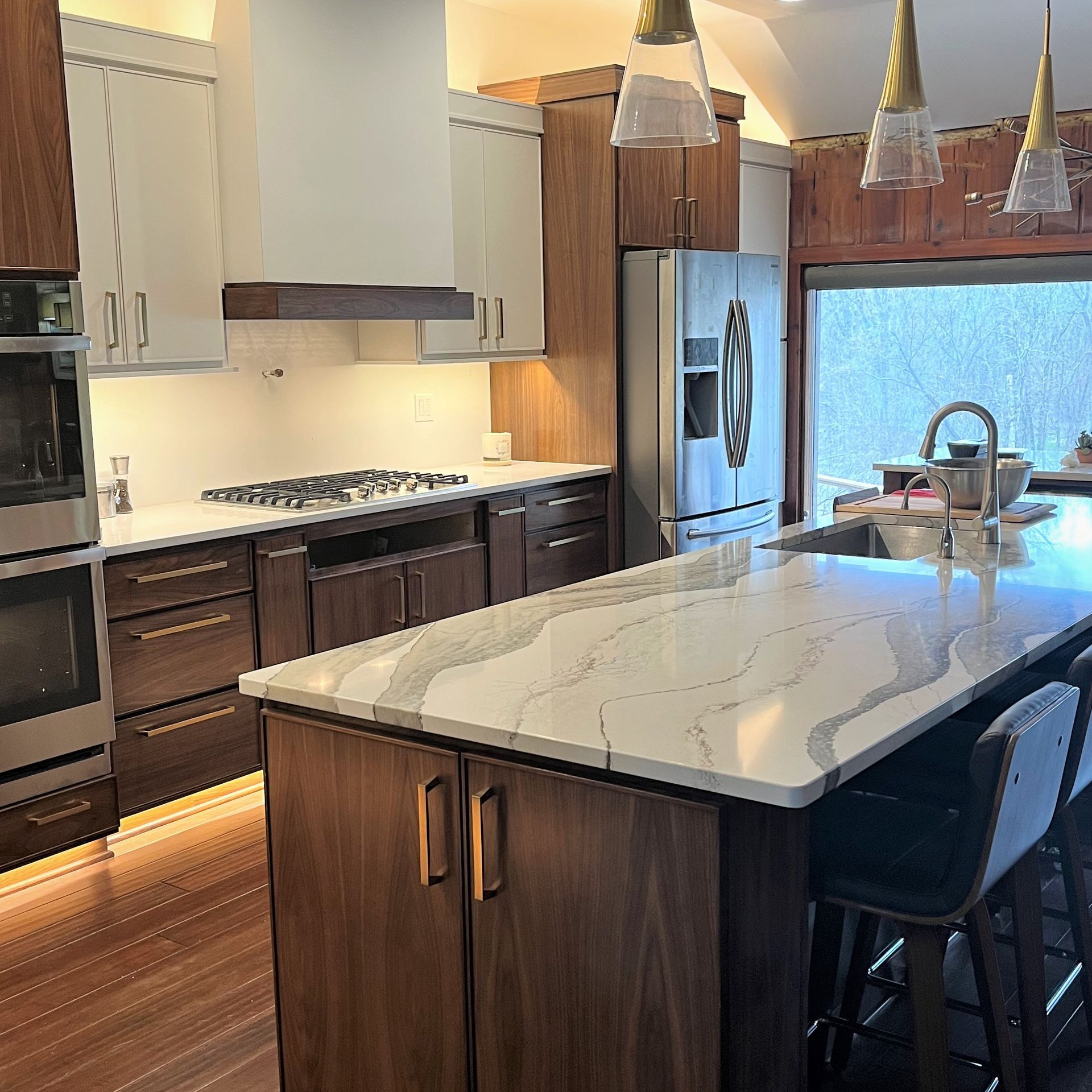 A modern kitchen with dark wood cabinets, white upper cabinets, marble-patterned countertops, and a central island.