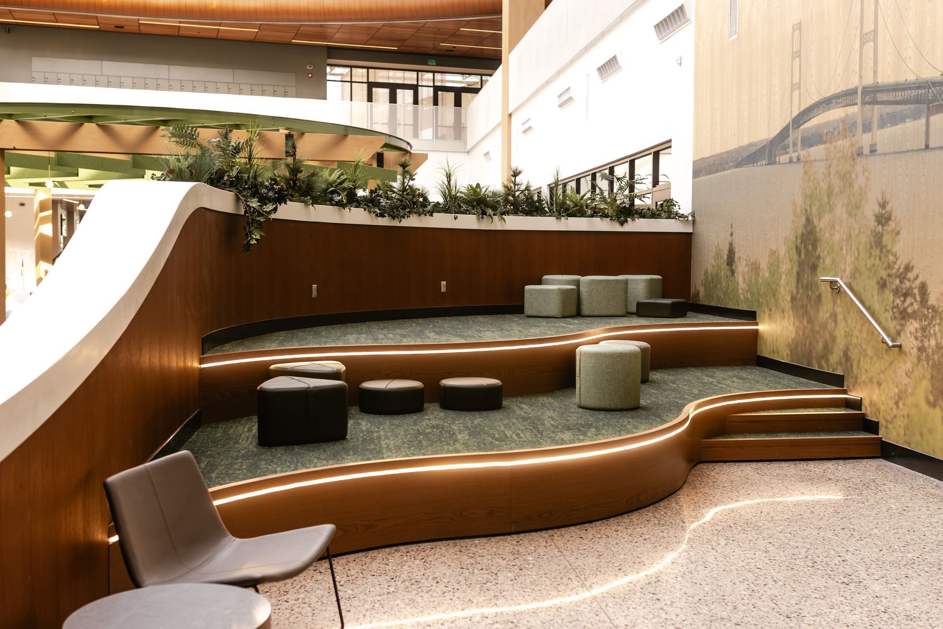 Modern lobby lounge with curved wooden seating, round cushions, and a white chair under warm lighting