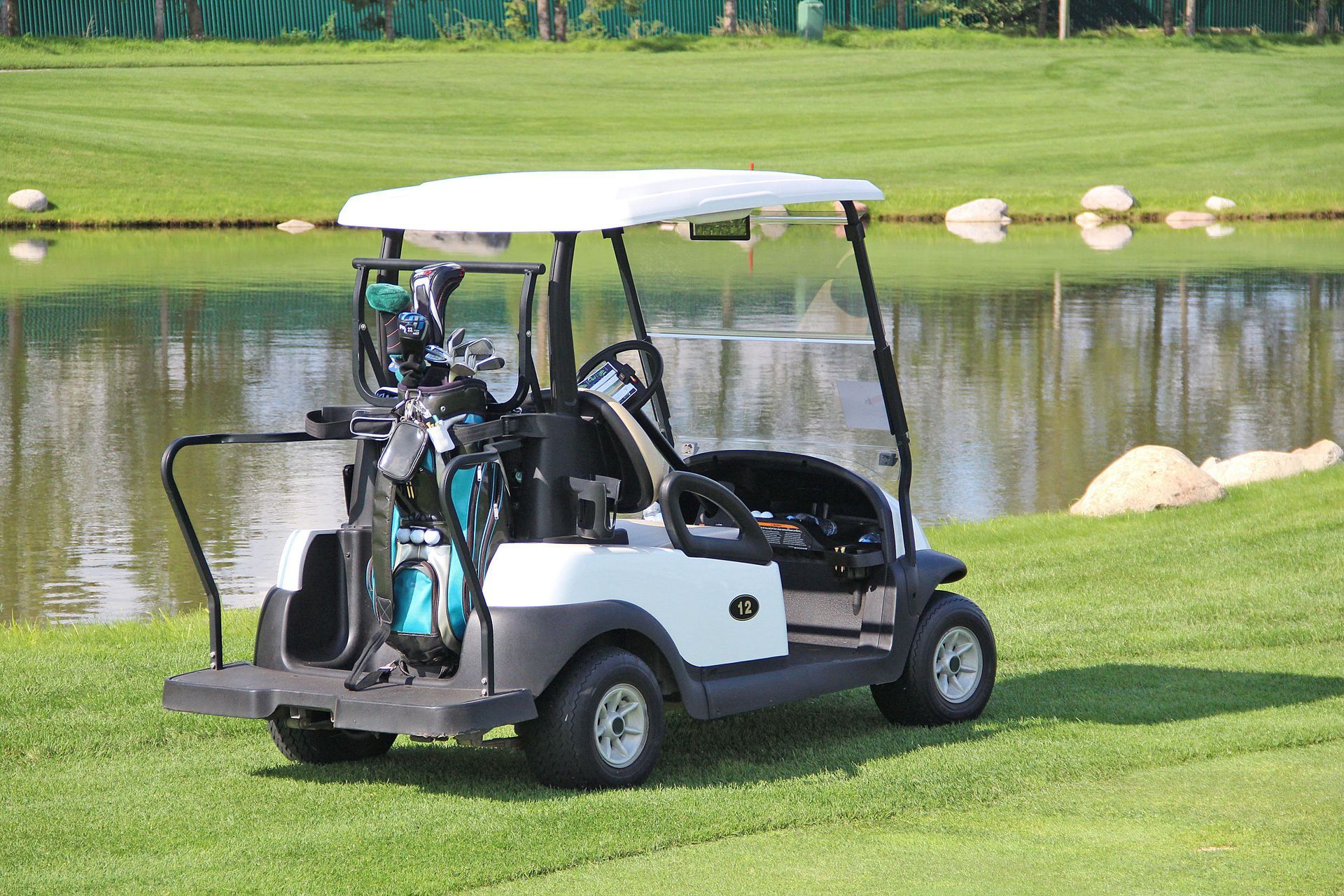 A golf cart is parked on a golf course next to a lake.