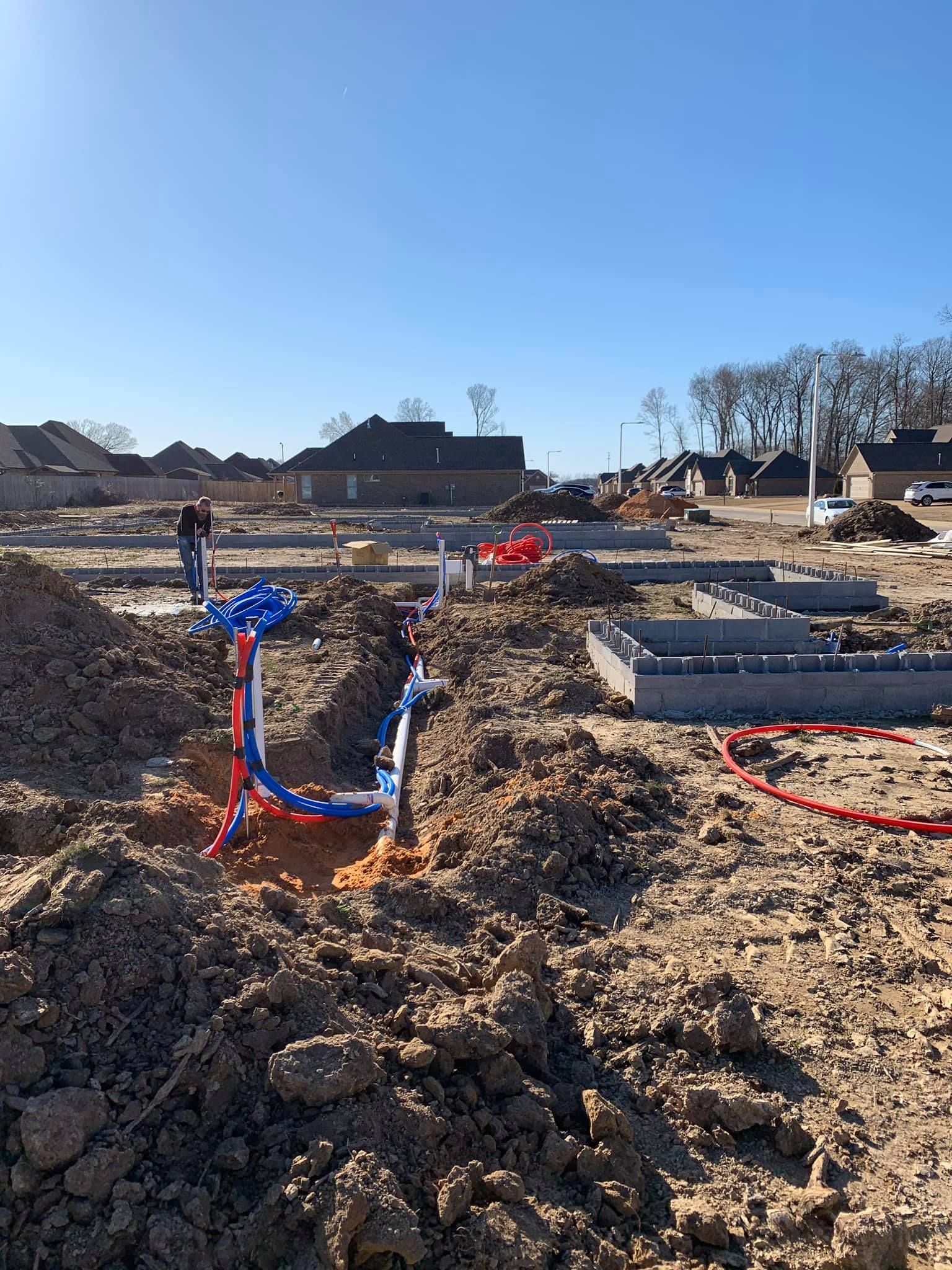 A construction site with a bunch of pipes in the dirt.