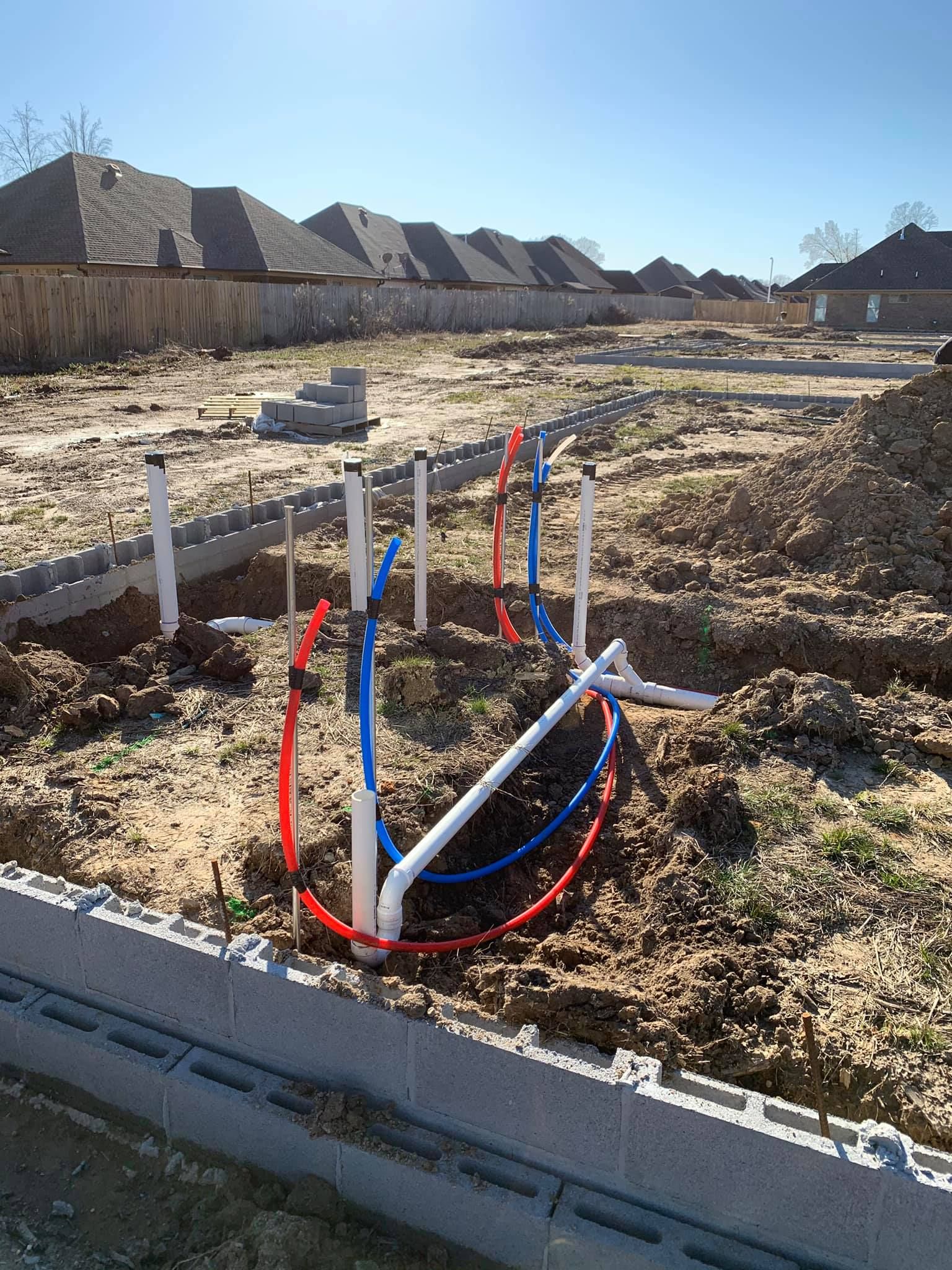 A construction site with a lot of pipes in the dirt.
