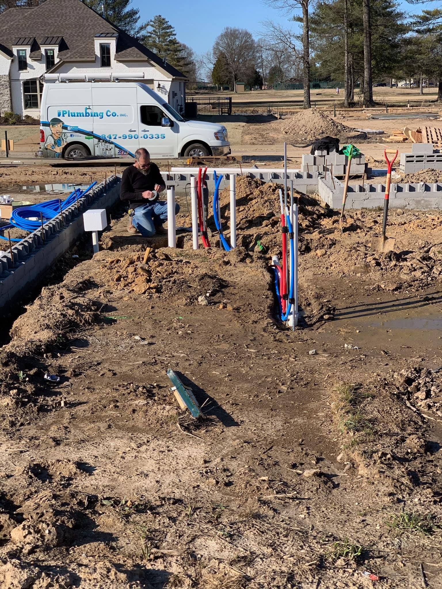 A man is sitting in the dirt next to a white van.
