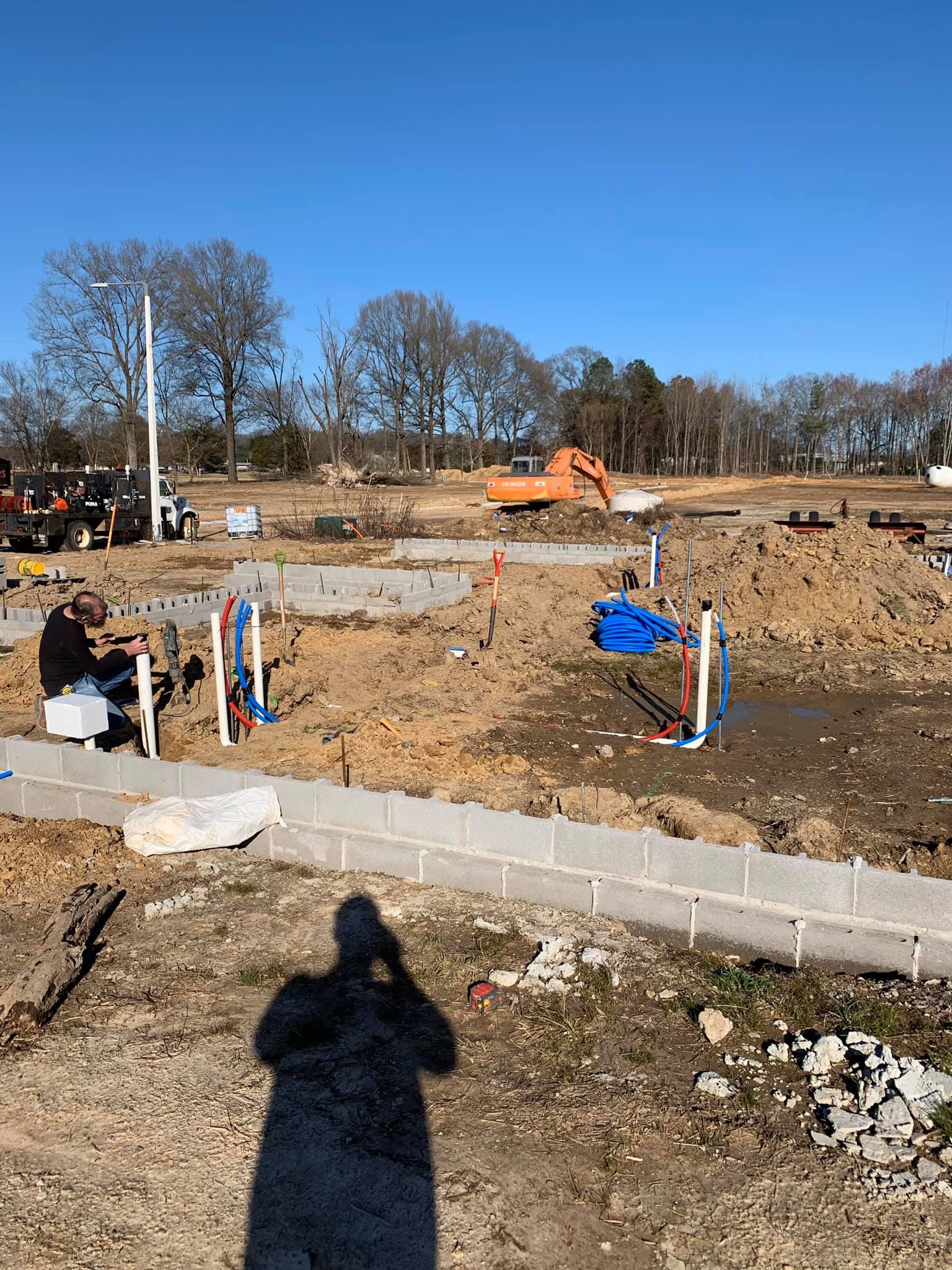 A man is sitting at a table in the middle of a construction site.