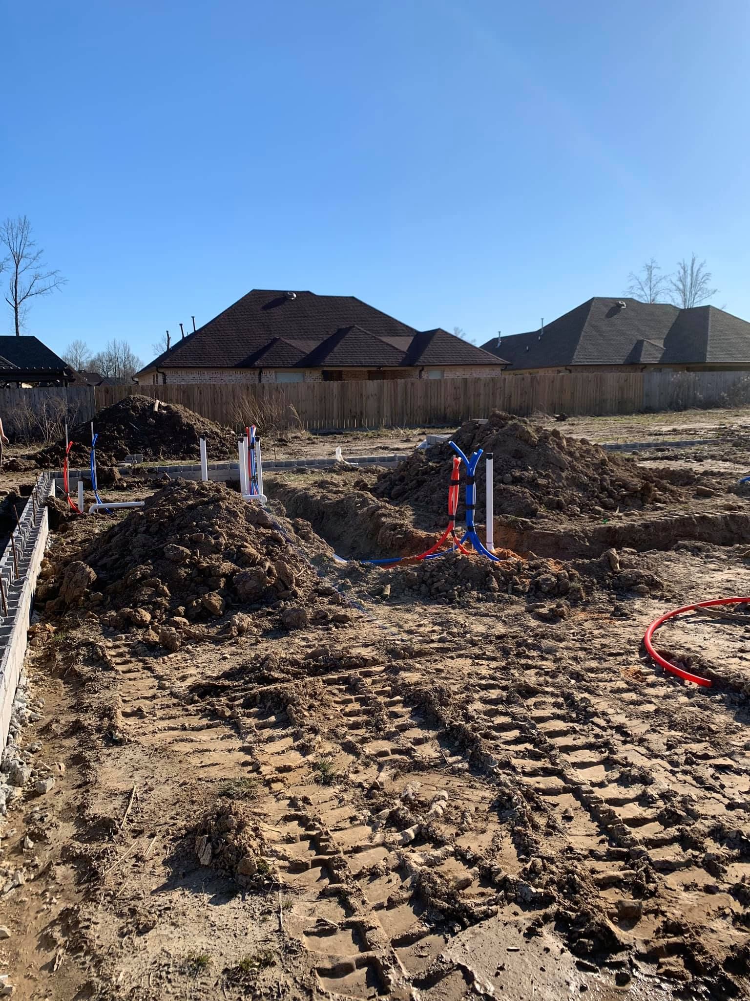 A construction site with a lot of dirt and houses in the background.