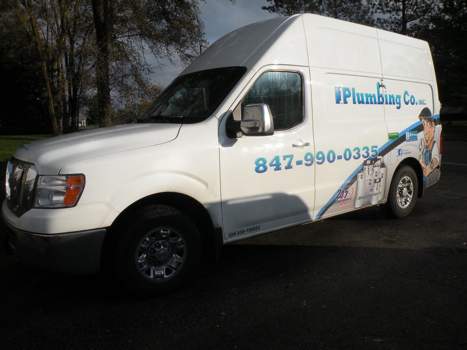 A plumbing company van is parked in a parking lot
