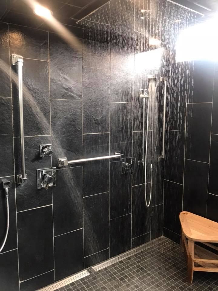 A bathroom with a walk in shower and a wooden bench.