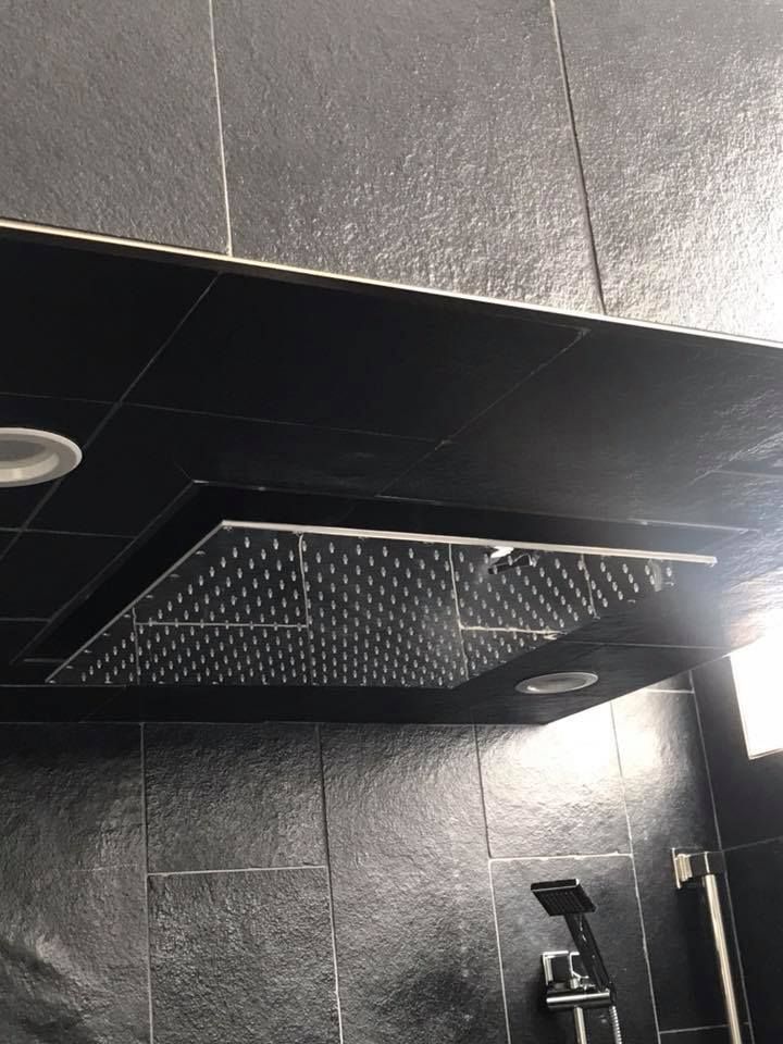 A shower head is hanging from the ceiling of a bathroom.