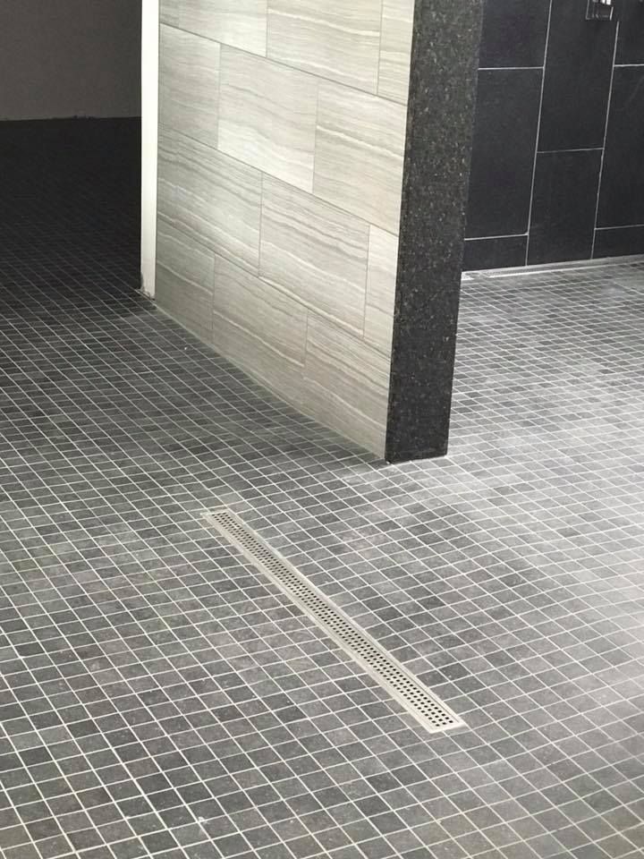 A tiled floor in a bathroom with a drain.