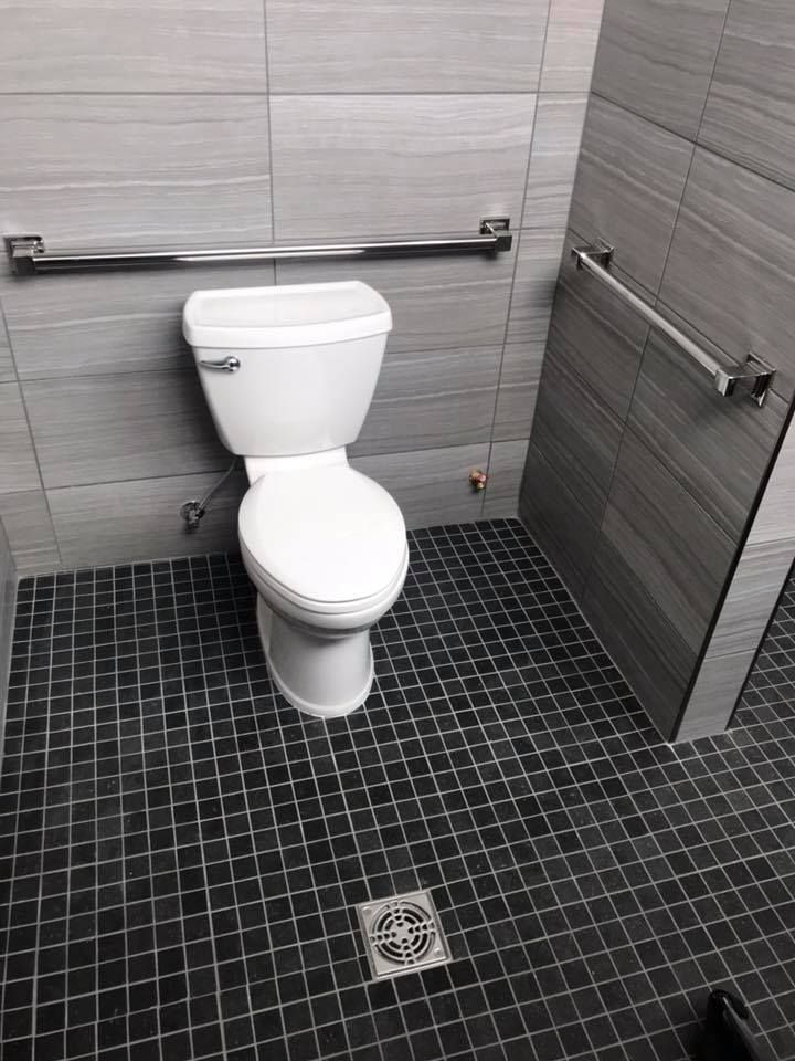 A toilet is sitting in a bathroom with a black tile floor.